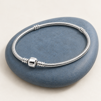 Bracelet argenté disposé en diagonale sur une céramique bleu ardoise