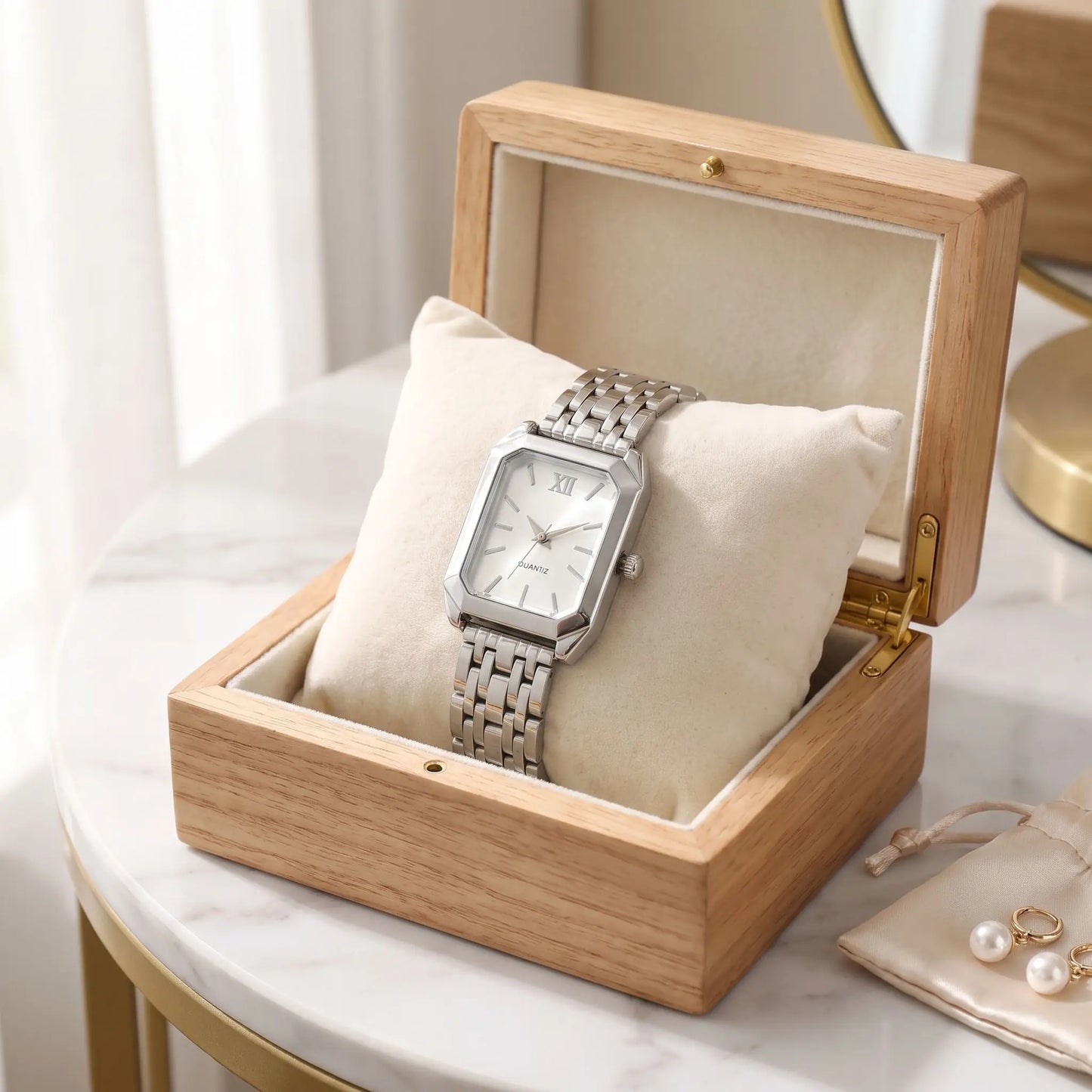 Montre rectangulaire femme oripse argent blanc posée sur une boîte à bijoux