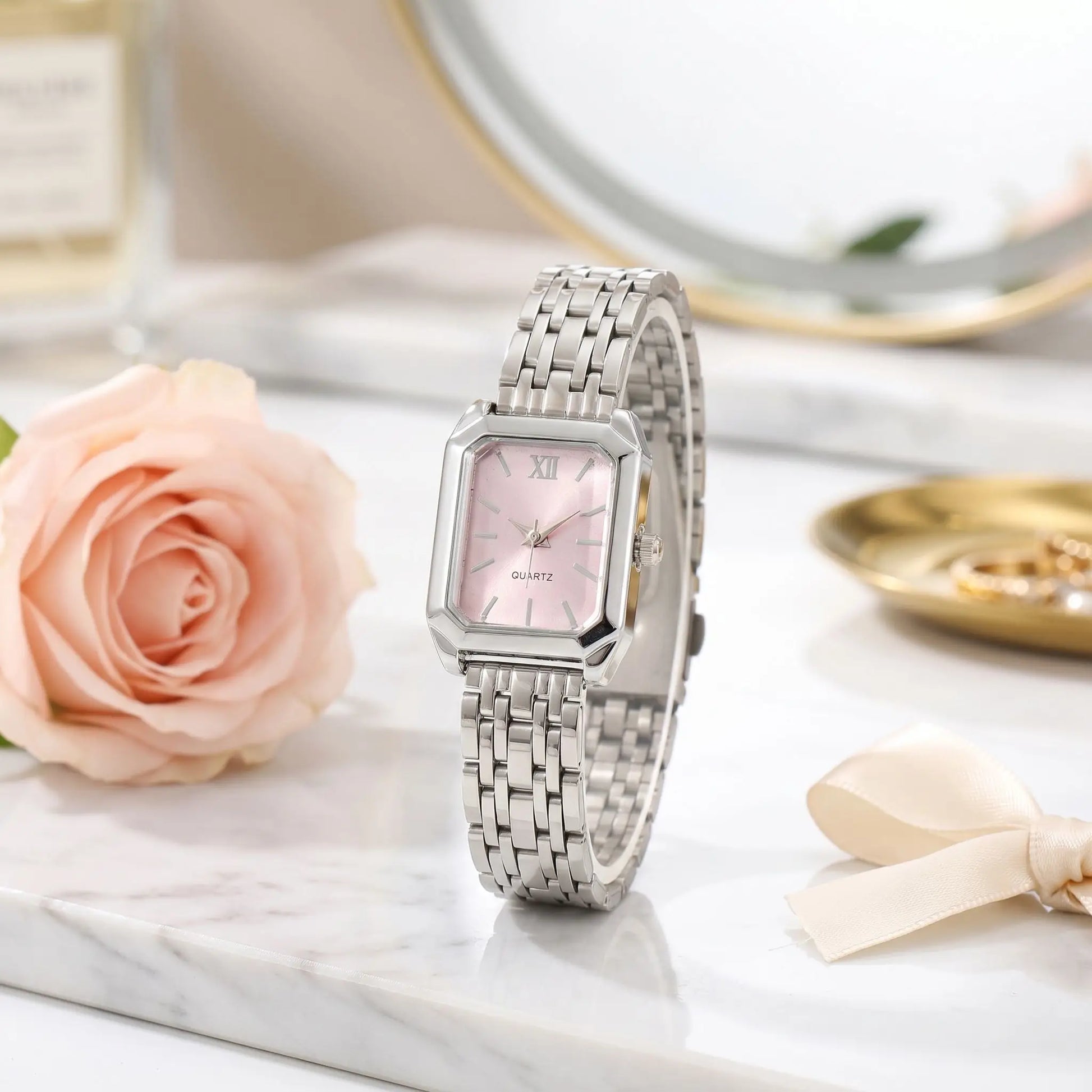 Montre rectangulaire femme Oripse argent rose posée sur un fond coloré